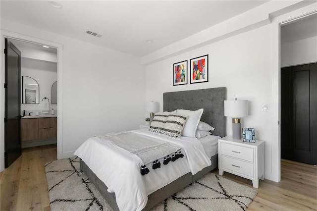 bedroom featuring connected bathroom and light hardwood / wood-style floors