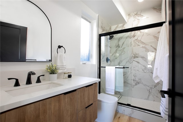 bathroom with a shower with door, vanity, and toilet