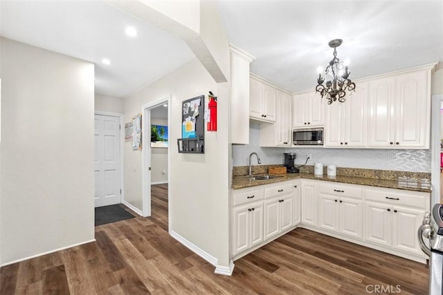 kitchen with stainless steel appliances, sink, dark stone counters, and white cabinets