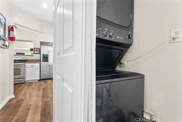 laundry room featuring stacked washer / drying machine and light wood-type flooring