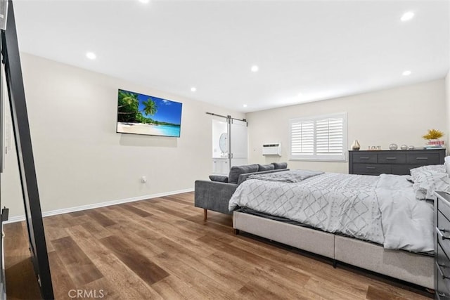 bedroom featuring a barn door and hardwood / wood-style floors