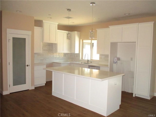 kitchen with a kitchen island, dark hardwood / wood-style floors, sink, white cabinets, and hanging light fixtures