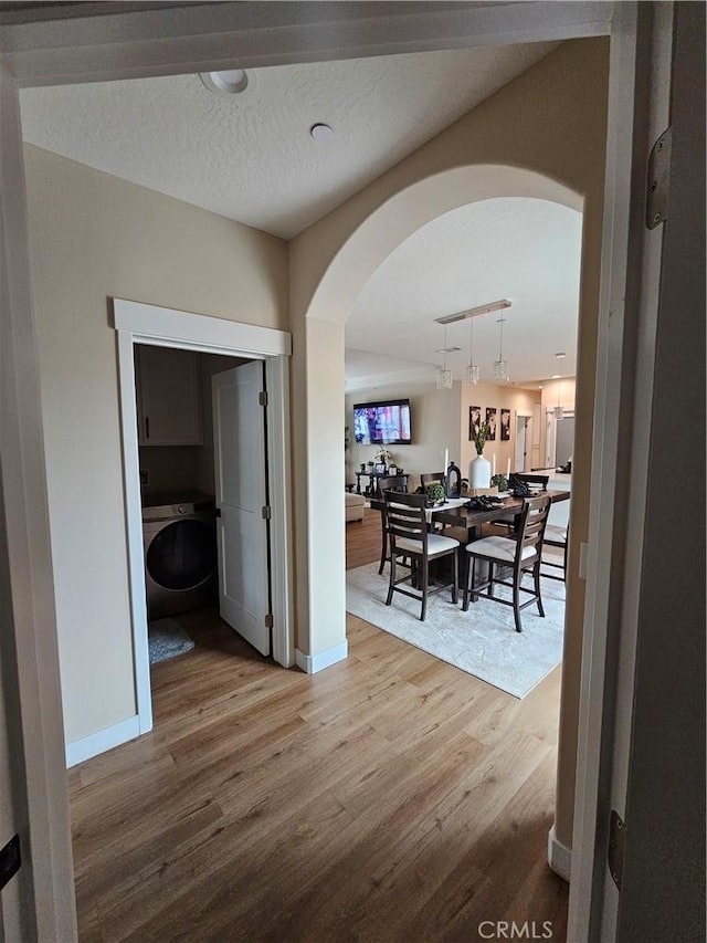 hall featuring washer / dryer, hardwood / wood-style floors, and a textured ceiling