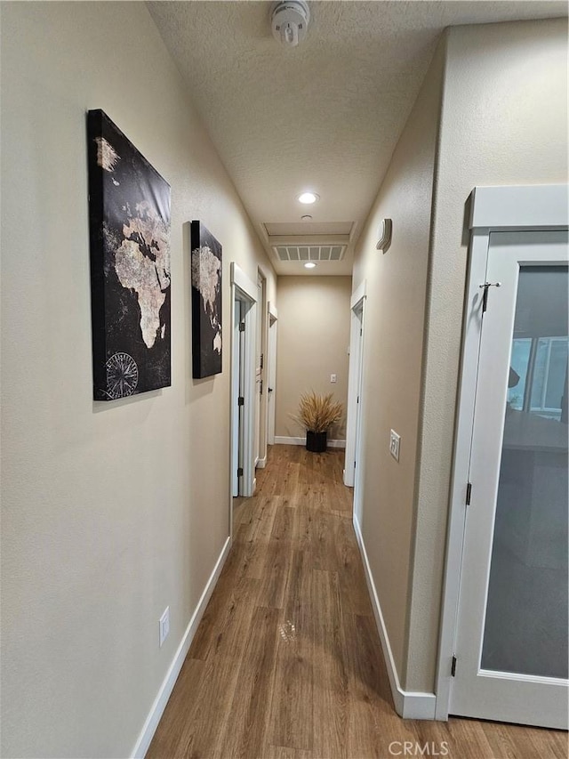 hallway with wood-type flooring and a textured ceiling