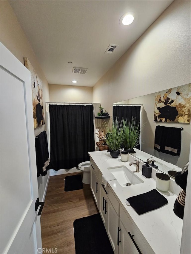 bathroom featuring vanity, hardwood / wood-style floors, toilet, and walk in shower