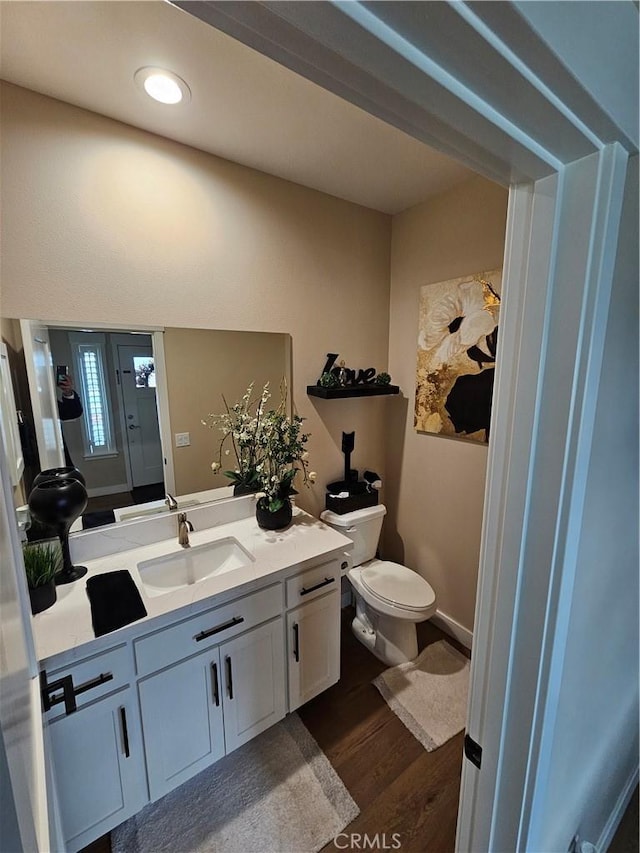 bathroom featuring wood-type flooring, vanity, and toilet