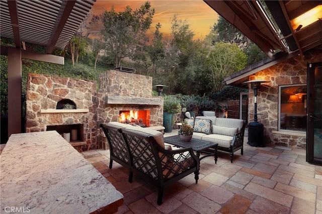 patio terrace at dusk with an outdoor living space with a fireplace