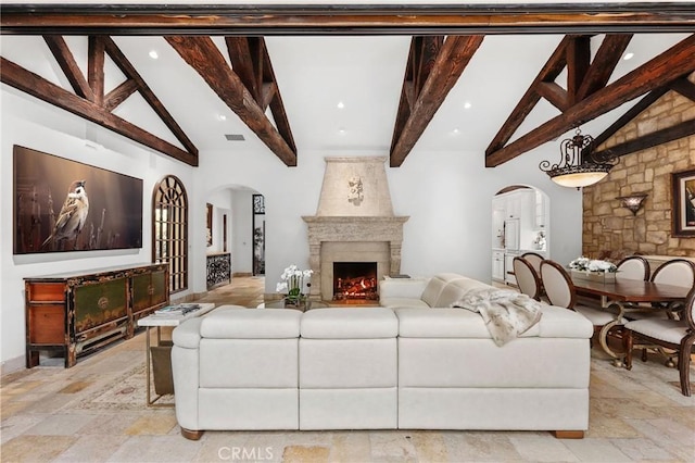 living room with a premium fireplace, high vaulted ceiling, and beam ceiling