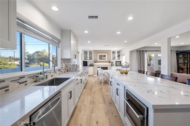 kitchen featuring appliances with stainless steel finishes, white cabinetry, decorative backsplash, sink, and a breakfast bar