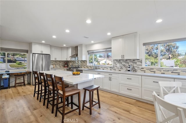 kitchen with a kitchen island, a kitchen bar, white cabinetry, and light hardwood / wood-style flooring