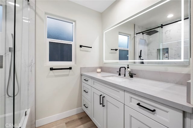 bathroom featuring vanity, hardwood / wood-style flooring, walk in shower, and plenty of natural light