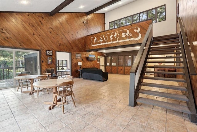 dining room with beam ceiling, light tile patterned floors, and wooden walls