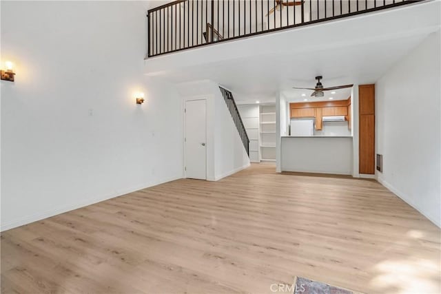 unfurnished living room featuring light wood-type flooring and ceiling fan