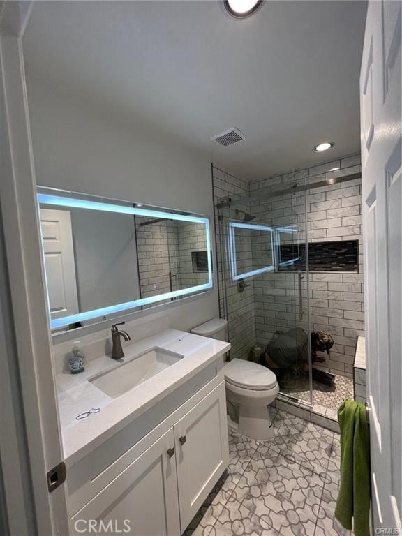 bathroom featuring vanity, toilet, and a shower with shower door