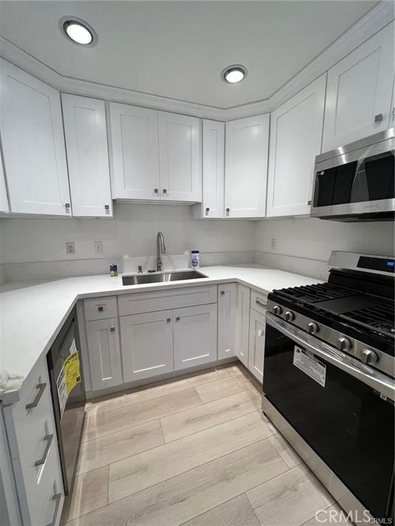 kitchen featuring white cabinetry, appliances with stainless steel finishes, light hardwood / wood-style floors, and sink