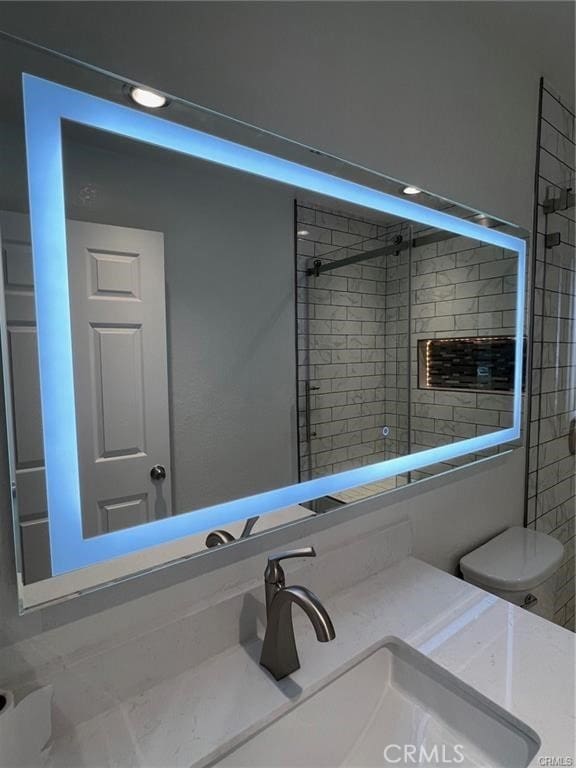 bathroom with toilet, vanity, and a shower with shower door