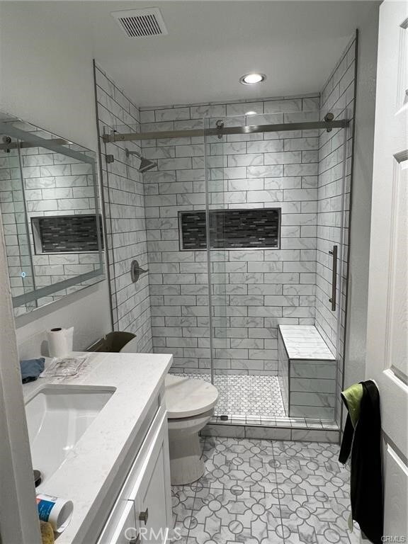 bathroom featuring a shower with door, toilet, tile patterned flooring, and vanity