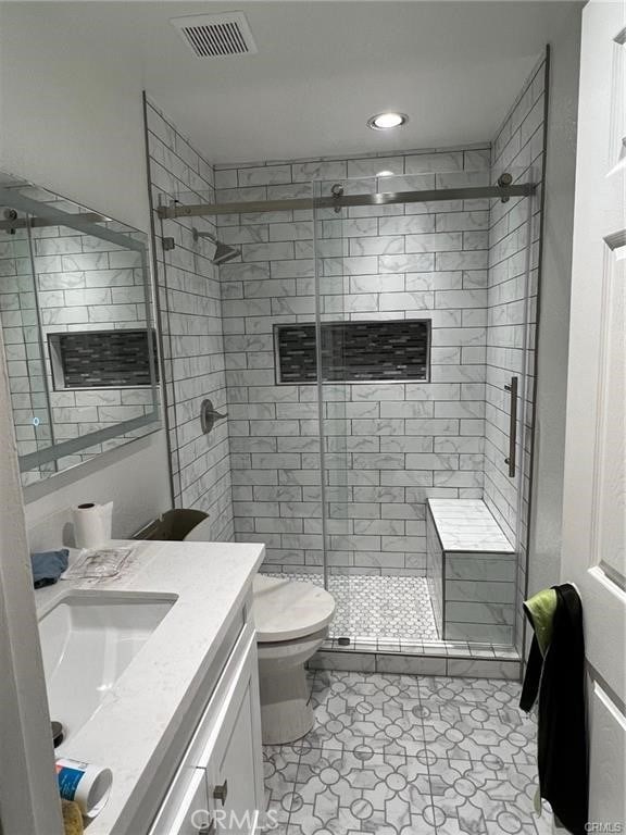 bathroom featuring vanity, toilet, and a shower with shower door