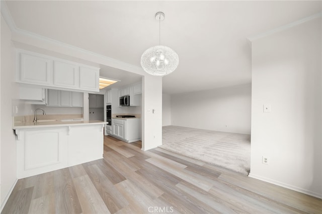 kitchen with kitchen peninsula, crown molding, hanging light fixtures, sink, and white cabinetry