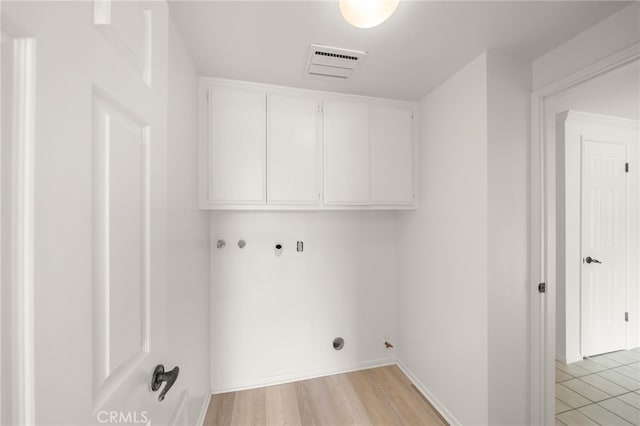 clothes washing area featuring cabinets, washer hookup, and light hardwood / wood-style flooring