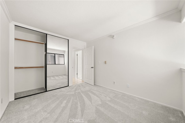 unfurnished bedroom with crown molding, a closet, and light carpet