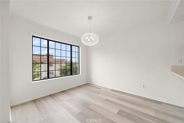 spare room featuring light hardwood / wood-style floors, a notable chandelier, and ornamental molding