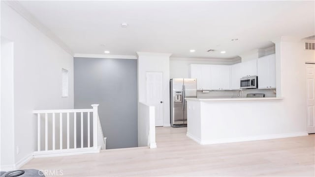 kitchen featuring white cabinetry, crown molding, light hardwood / wood-style flooring, and appliances with stainless steel finishes