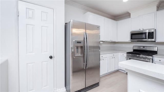 kitchen featuring white cabinetry, ornamental molding, appliances with stainless steel finishes, and light hardwood / wood-style floors