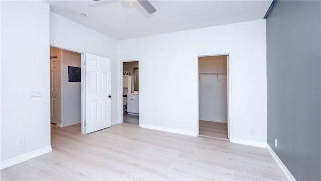 unfurnished bedroom with connected bathroom, a spacious closet, ceiling fan, light wood-type flooring, and a closet