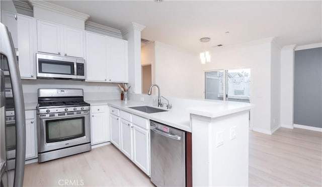 kitchen featuring sink, appliances with stainless steel finishes, hanging light fixtures, white cabinets, and kitchen peninsula