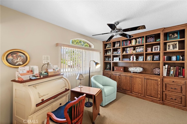 sitting room with a textured ceiling, light colored carpet, and ceiling fan