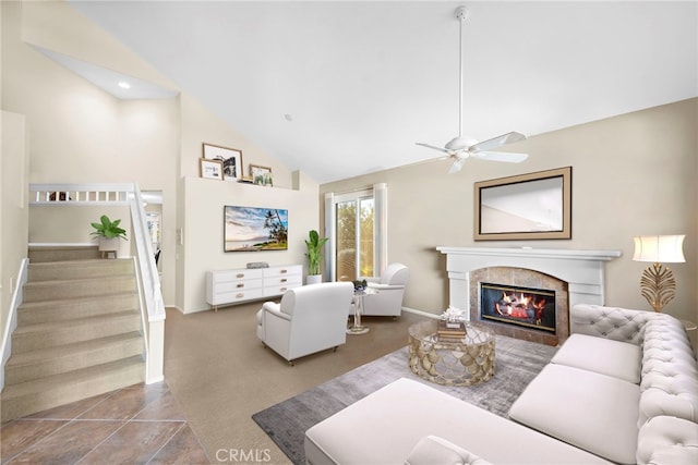 tiled living room featuring ceiling fan, a tile fireplace, and vaulted ceiling