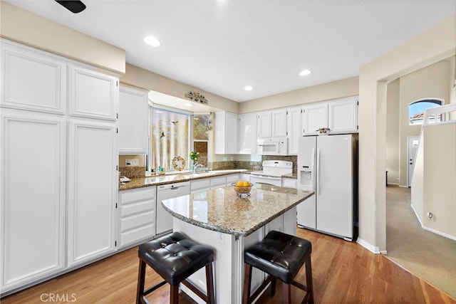 kitchen with white appliances, white cabinets, and light stone counters