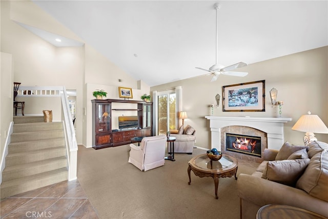 tiled living room with ceiling fan, high vaulted ceiling, and a tiled fireplace