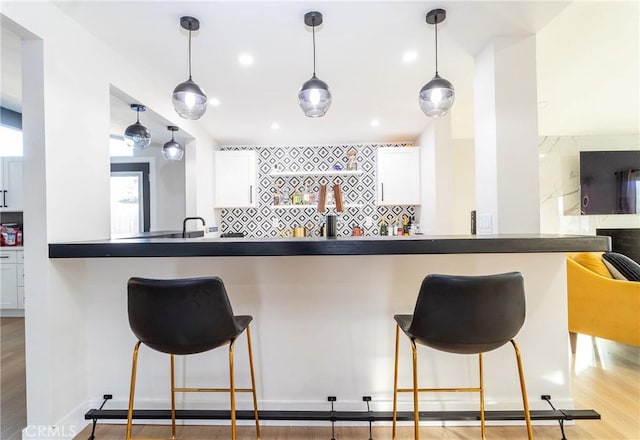 kitchen with hanging light fixtures, white cabinets, a breakfast bar area, and tasteful backsplash