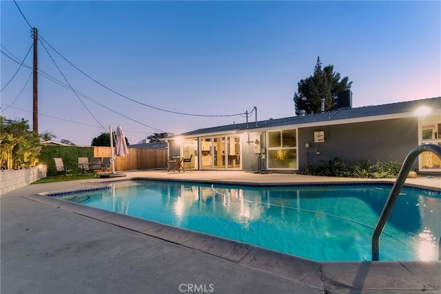 pool at dusk featuring a patio and central AC unit