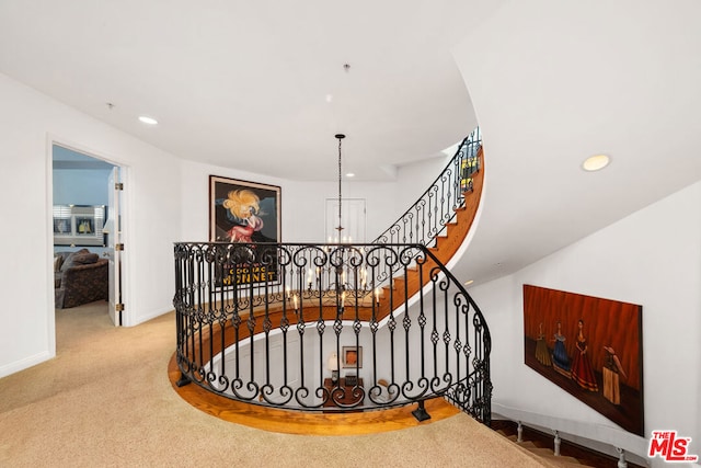 staircase featuring a notable chandelier and carpet