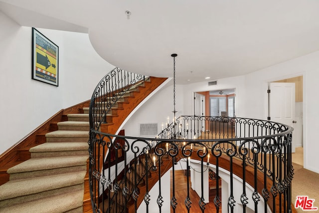 stairs with carpet and a notable chandelier