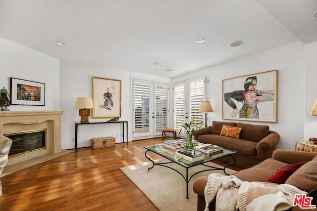 living room featuring a high end fireplace and light hardwood / wood-style flooring