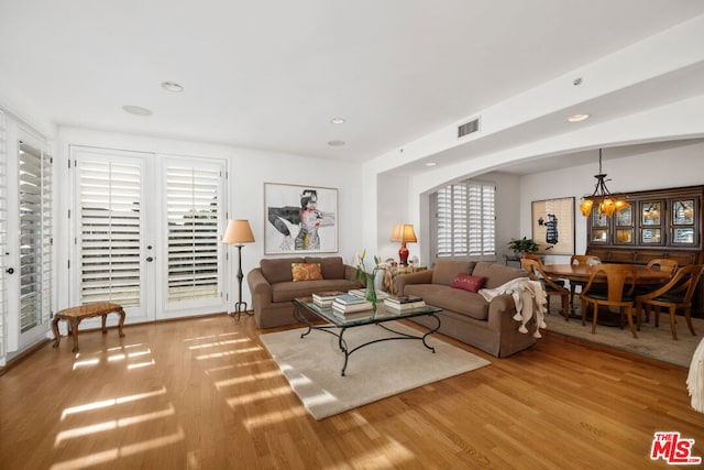 living room featuring plenty of natural light, a chandelier, and light wood-type flooring