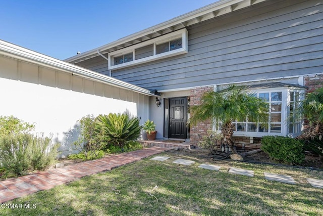 view of exterior entry with a yard