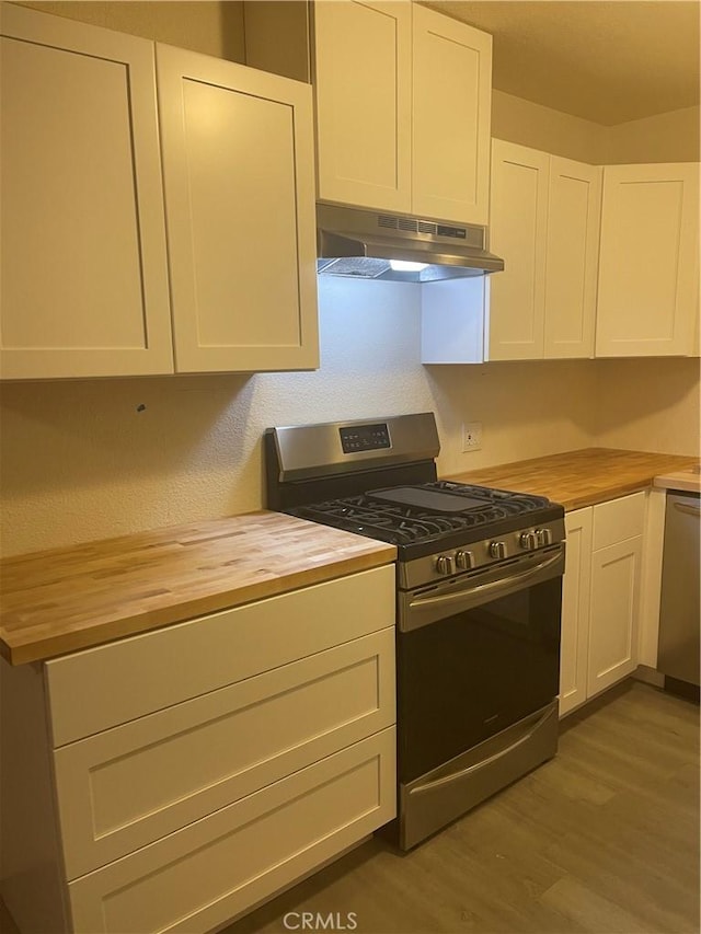 kitchen with stainless steel appliances, hardwood / wood-style flooring, white cabinets, and butcher block countertops