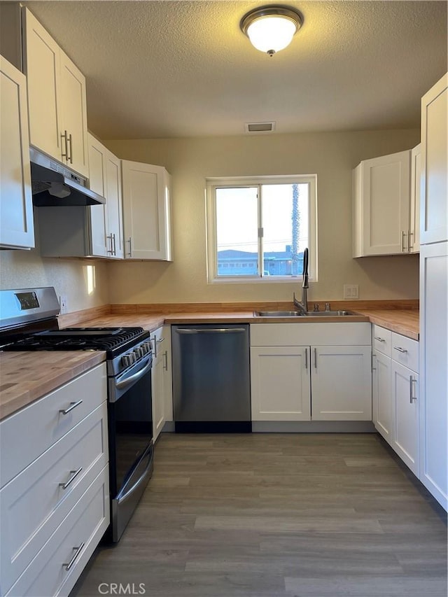 kitchen with white cabinetry, dishwasher, a textured ceiling, and stainless steel gas stove