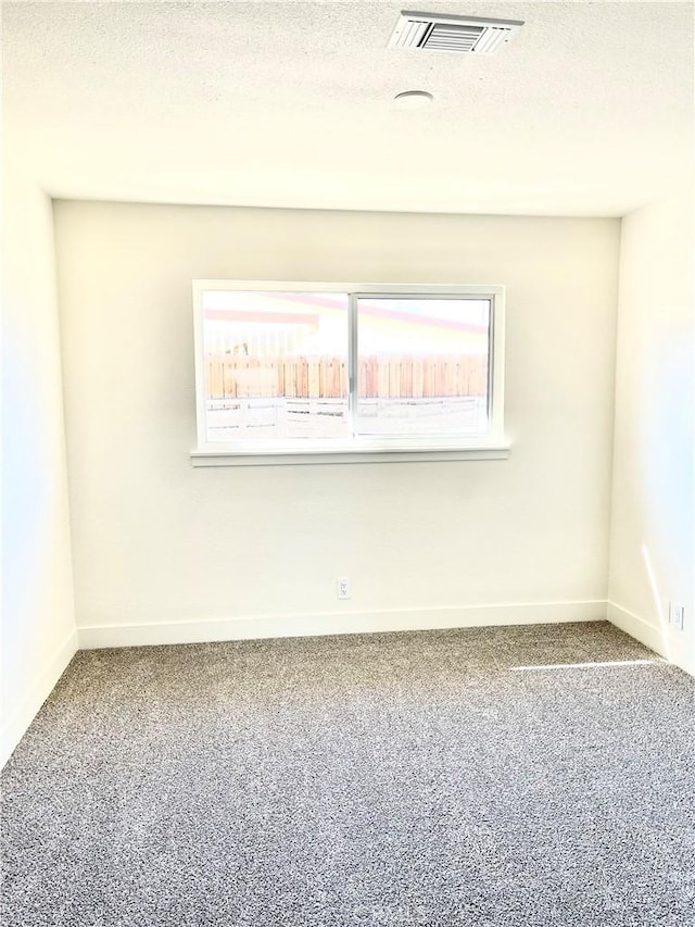 carpeted empty room featuring visible vents, a textured ceiling, and baseboards