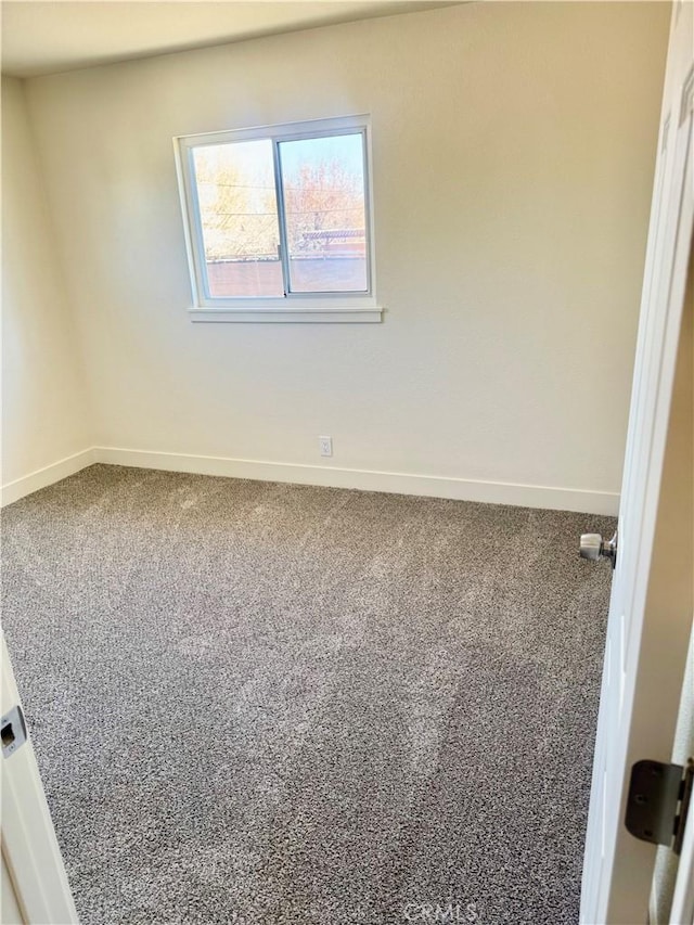 unfurnished room with carpet and baseboards