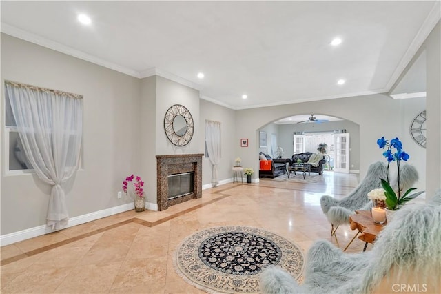 living room featuring ceiling fan, a high end fireplace, and crown molding