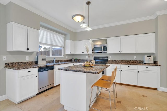 kitchen with white cabinets, a kitchen island, appliances with stainless steel finishes, and decorative light fixtures