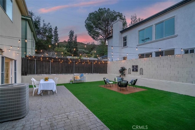 yard at dusk featuring a patio and central AC