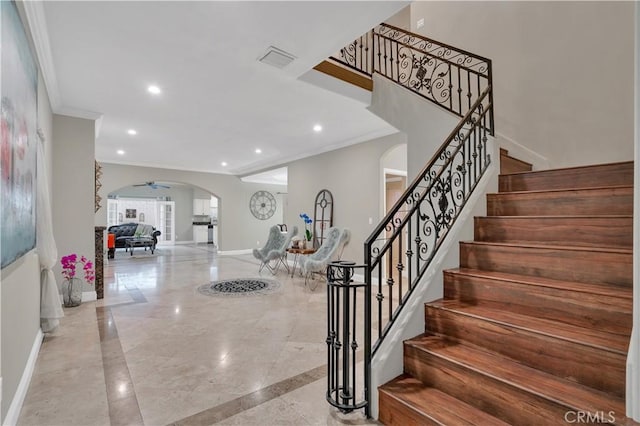 foyer with ceiling fan and crown molding