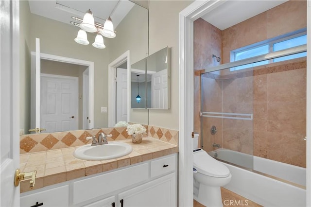 full bathroom featuring combined bath / shower with glass door, an inviting chandelier, toilet, and vanity